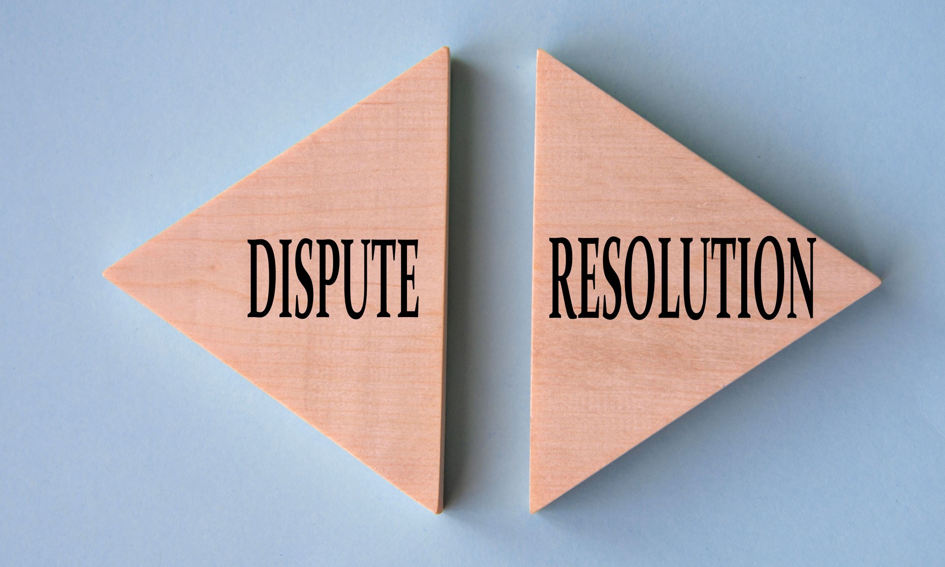 DISPUTE and RESOLUTION - words on wooden triangles on grey-blue background