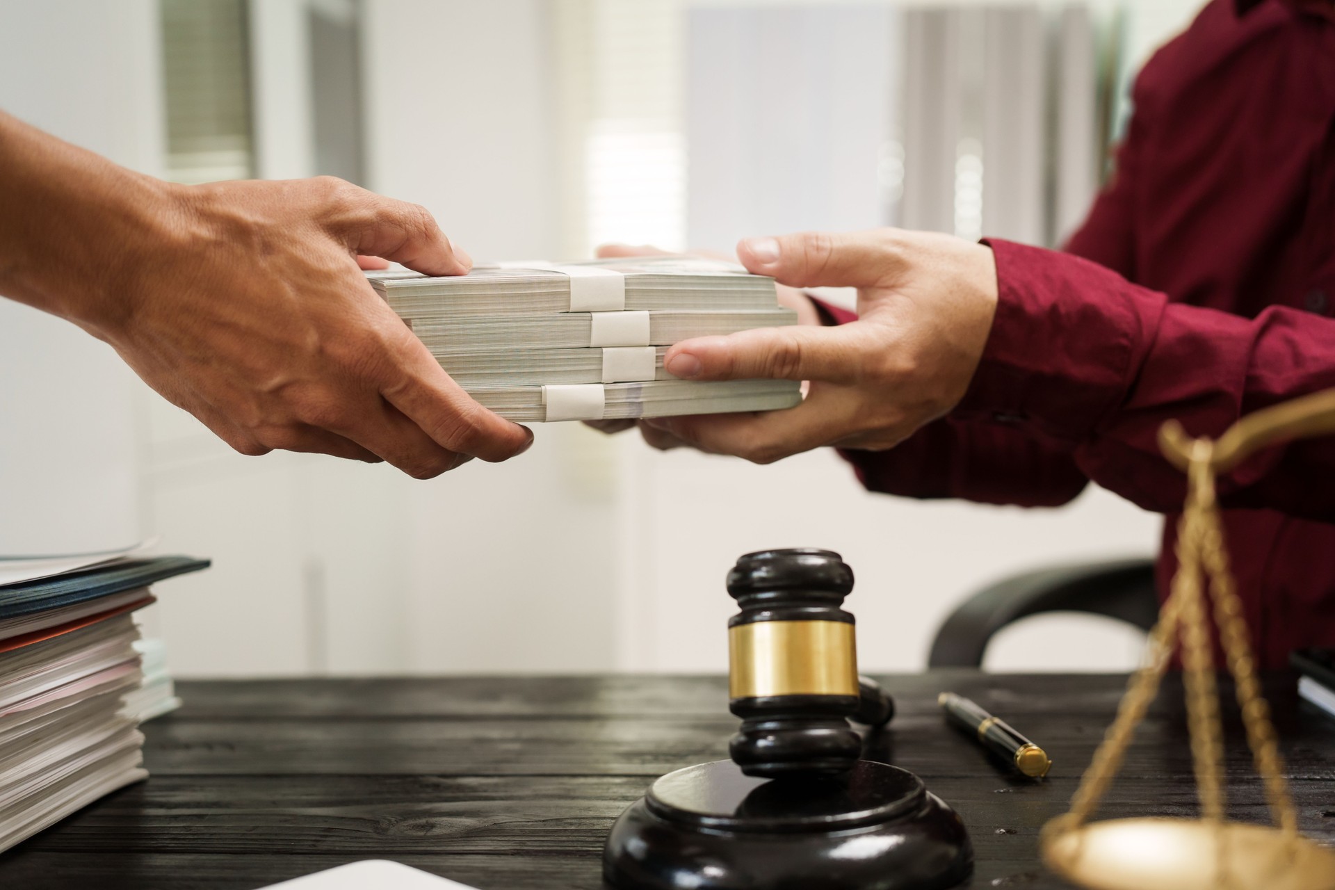 A male lawyer works at his desk, receiving cash from a client while considering the case. He focuses on law, justice, fairness, and the observance of legal rules and conventions in the system